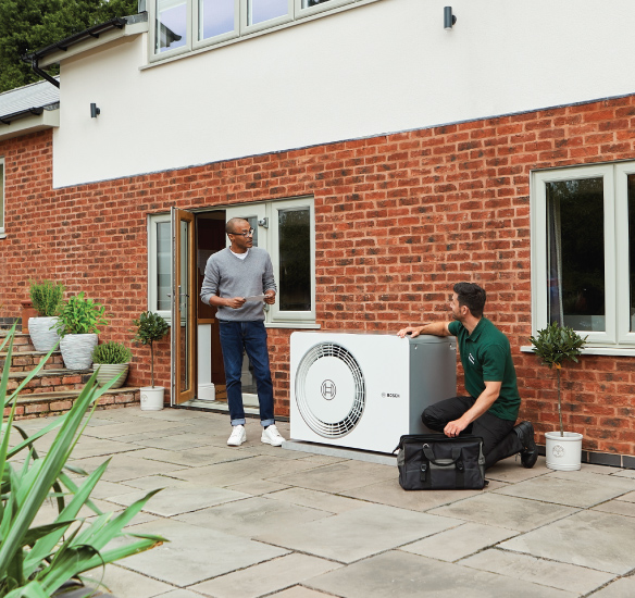 Installer fitting heat pump outside with homeowner